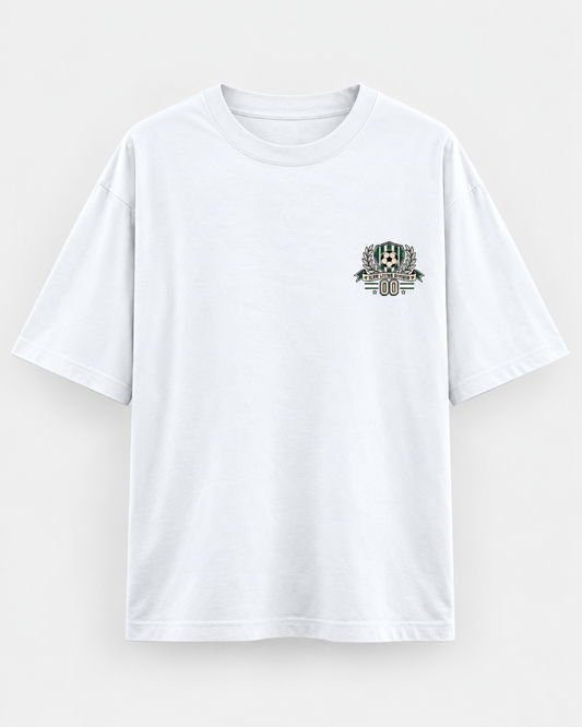White oversized football T-shirt with a small green and cream soccer crest graphic on the chest.