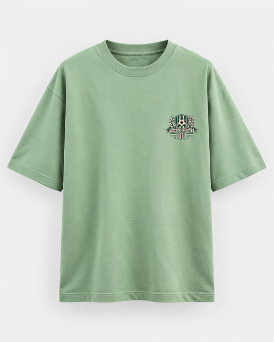 Jade green oversized football T-shirt with a small green and cream soccer crest graphic on the chest.